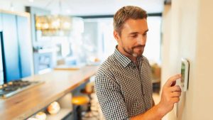 man adjusting thermostat