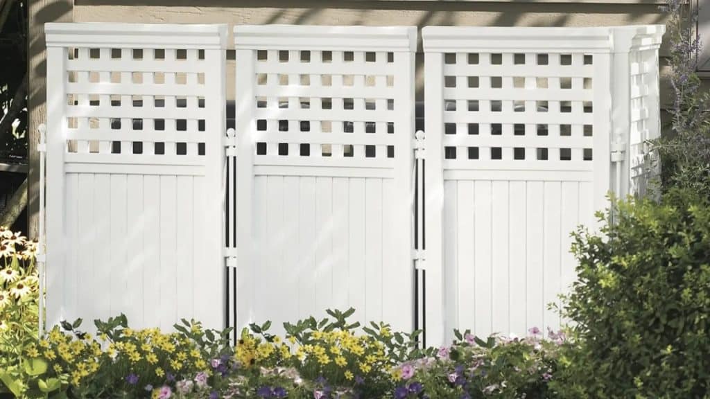 hiding an hvac unit with A white fence with lattice panels in front of a flowerbed.
