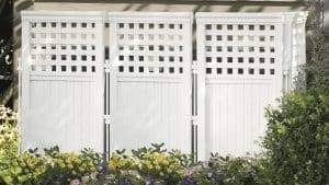 hiding an hvac unit with A white fence with lattice panels in front of a flowerbed.