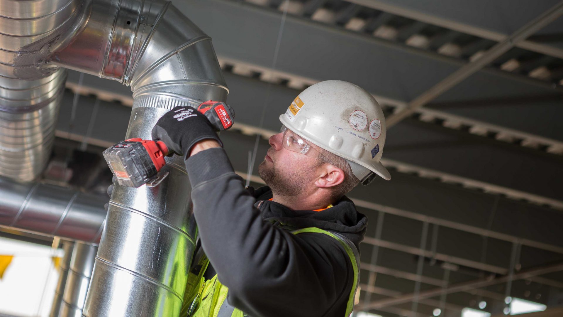 A construction worker is working on a pipe in a building.